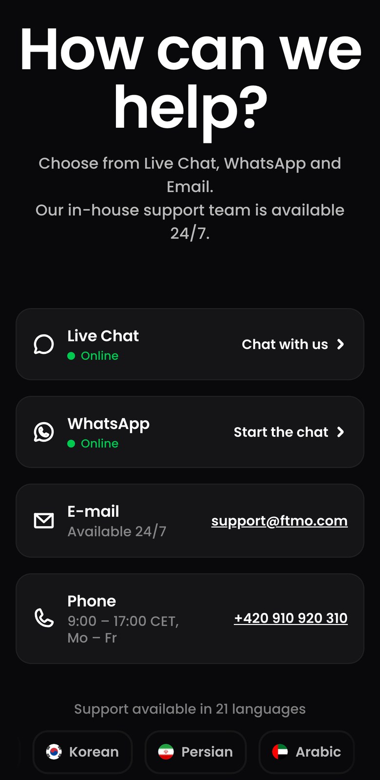 FTMO公式サイトの問い合わせページ（スマホ表示）。Live ChatとWhatsAppはOnline、E-mailはAvailable 24/7でsupport@ftmo.com、Phoneは9:00〜17:00 CETの月〜金で+420 910 920 310と書かれている。その下に対応21言語の帯がある